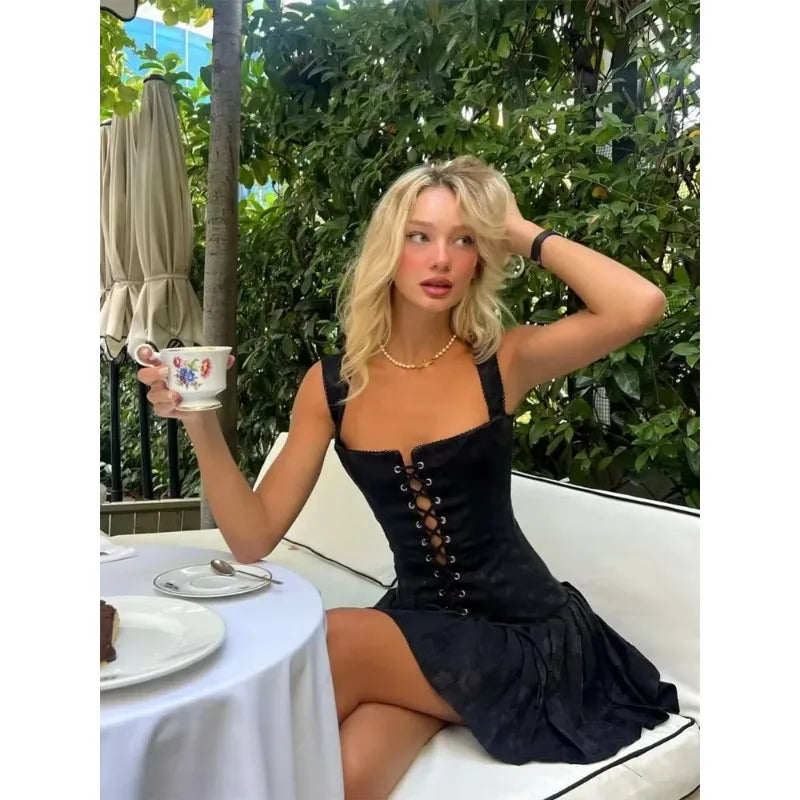 Woman in a black dress holding a floral teacup outdoors